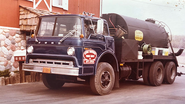 plm sealcoat truck in front of barn vintage
